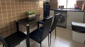 A compact kitchen with a dining area, a washing machine, and a window. - Cosy 2-bed flat in the heart of SoHo! (London)