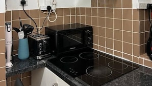 A kitchen with a black stove, a microwave, and a built-in oven. There is a water dispenser on the wall and a glass hood above the stove. - Cosy 2-bed flat in the heart of SoHo! (London)