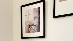 A framed picture on a wall with a small glass object on a table below. - Cosy 2-bed flat in the heart of SoHo! (London)