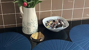 A tiled wall, a white vase with tulips, a bowl of chocolates, and blue round tables. - Cosy 2-bed flat in the heart of SoHo! (London)