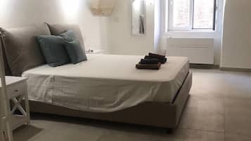 A bedroom with a bed, pillows, a bedside table, a mirror, and a window.