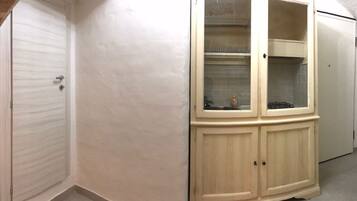 Un pasillo con un armario color crema con puertas de vidrio, una puerta blanca y un refrigerador blanco.