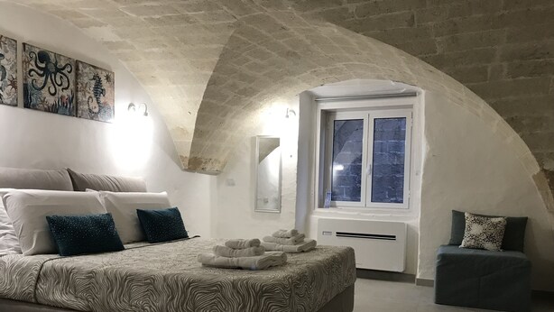 Un dormitorio con una cama grande, un espacio de descanso pequeño, una ventana con vistas y obras de arte en la pared.