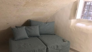 Un sofá de esquina con ventana y pared con textura.