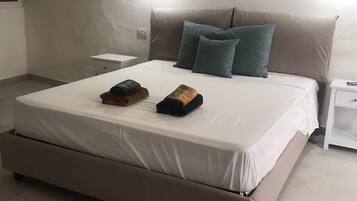 Une chambre à coucher avec un grand lit, deux oreillers, une table de chevet et un mur orné de trois œuvres d’art.