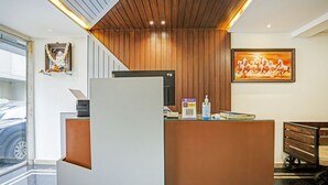 A reception desk with a wooden panel backdrop, a framed picture of horses, and a QR code for digital services. - Itsy Hotels Purple Suites (Bengaluru)