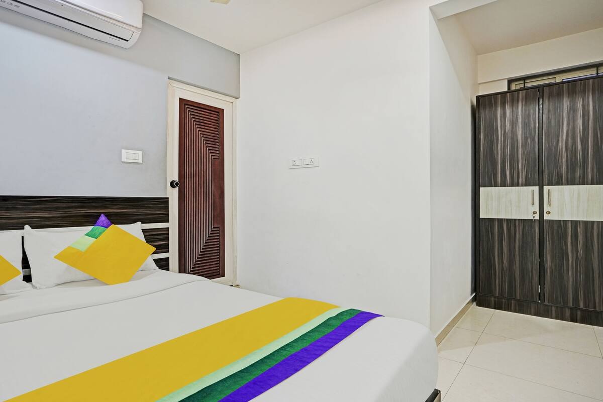 A hotel room with a bed, a wardrobe, and an air conditioning unit.