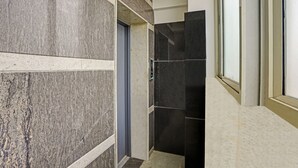 A hallway with marble walls, a door, and a tiled wall. - Itsy Hotels Purple Suites (Bengaluru)