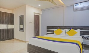 A hotel room with a bed, a wardrobe, a door, and an air conditioning unit. - Itsy Hotels Purple Suites (Bengaluru)