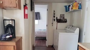Un couloir étroit avec un lave-linge, des placards en bois et une machine à café.