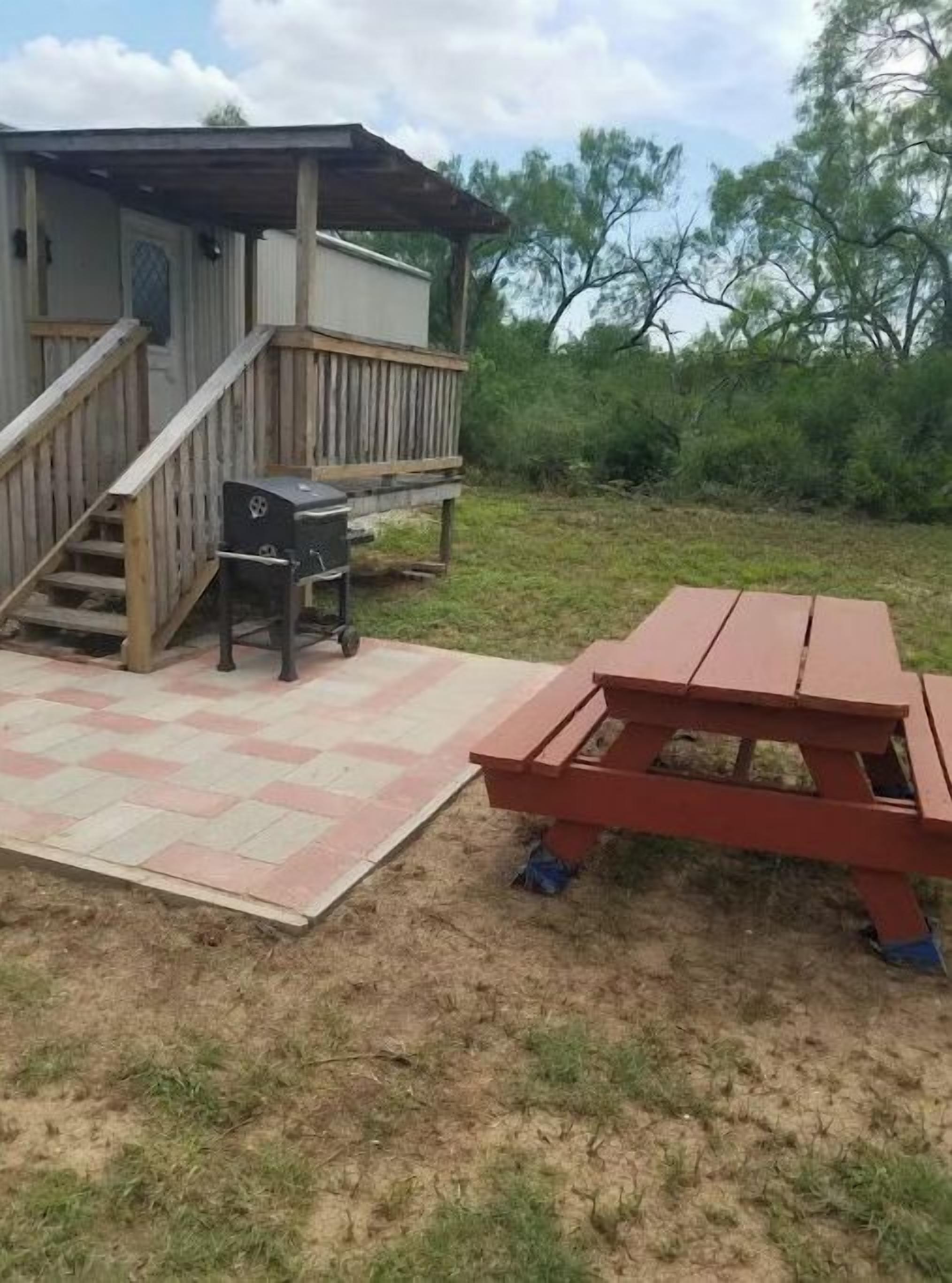 A wooden deck with a picnic table and barbecue grill.