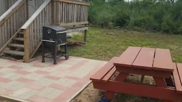 A wooden deck with a picnic table and barbecue grill.