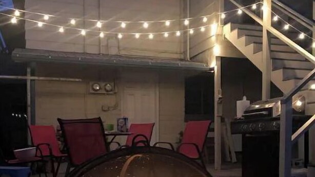An outdoor patio with a fire pit, string lights, and a staircase. - Blue Skye: Downtown Getaway (Bishop)