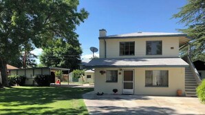 A two-story house with a covered patio, a front door, and a small porch area. - Blue Skye: Downtown Getaway (Bishop)
