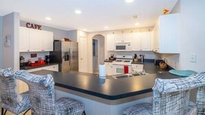 A modern kitchen with white cabinets, a central island, and bar-style seating. - Luxurious Relaxing Retreat (Davenport)