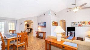 A spacious living room with a wooden dining table, a sofa, and a ceiling fan. - Luxurious Relaxing Retreat (Davenport)