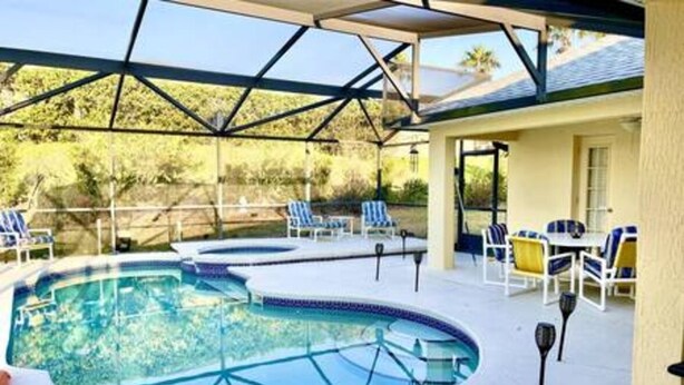 An outdoor swimming pool with lounge chairs and a covered patio area. - Luxurious Relaxing Retreat (Davenport)