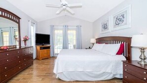 A bedroom with a bed, dresser, TV, and ceiling fan. - Luxurious Relaxing Retreat (Davenport)