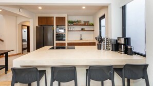 Uma cozinha moderna com uma ilha grande, eletrodomésticos embutidos e um balcão para refeições rápidas.