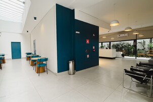 Una hall d'hotel moderna con reception, area salotto e ampie finestre.