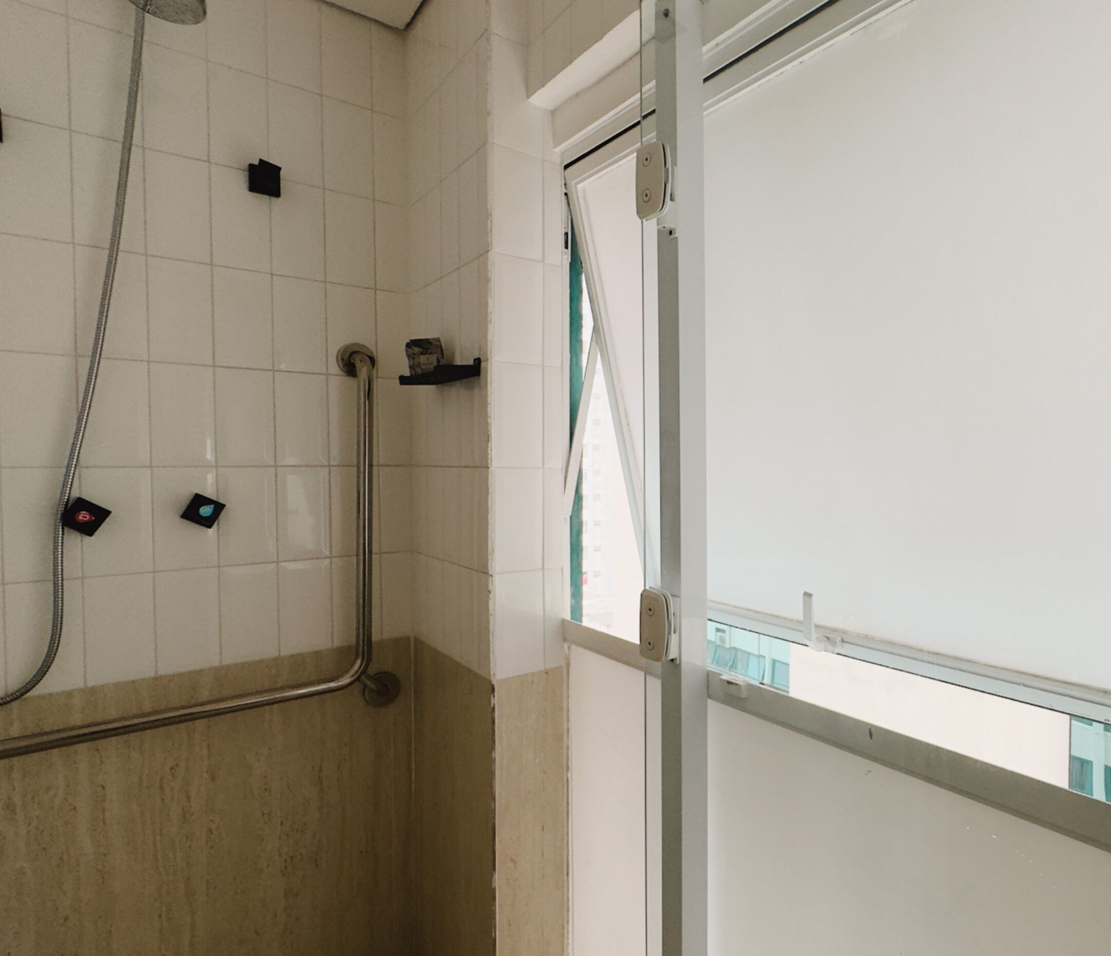 A shower area with a glass door, tiled walls, and a visible window.