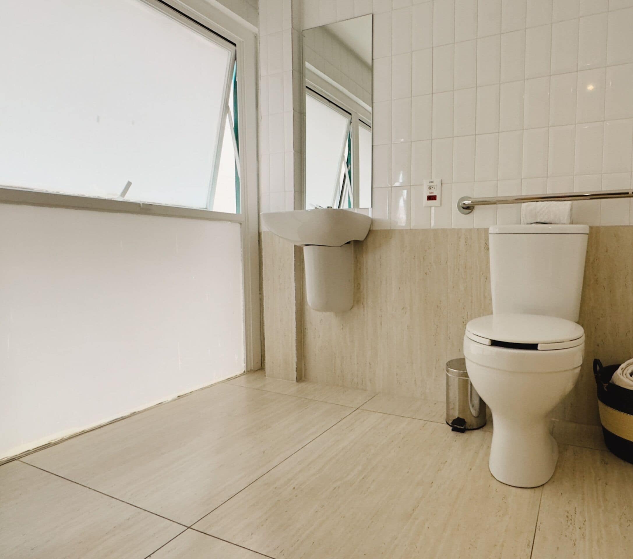A modern bathroom with a toilet, a sink, and a trash bin.
