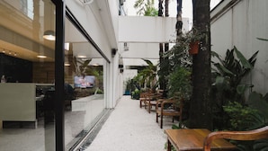 An indoor seating area with wooden benches and tables, surrounded by potted plants and a gravel floor. - Apê Bela Cintra (São Paulo)
