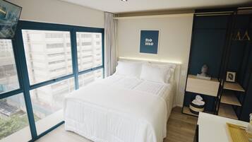 A modern hotel room with a large bed, a view of the city through a large window, and a 'home' sign on the wall.