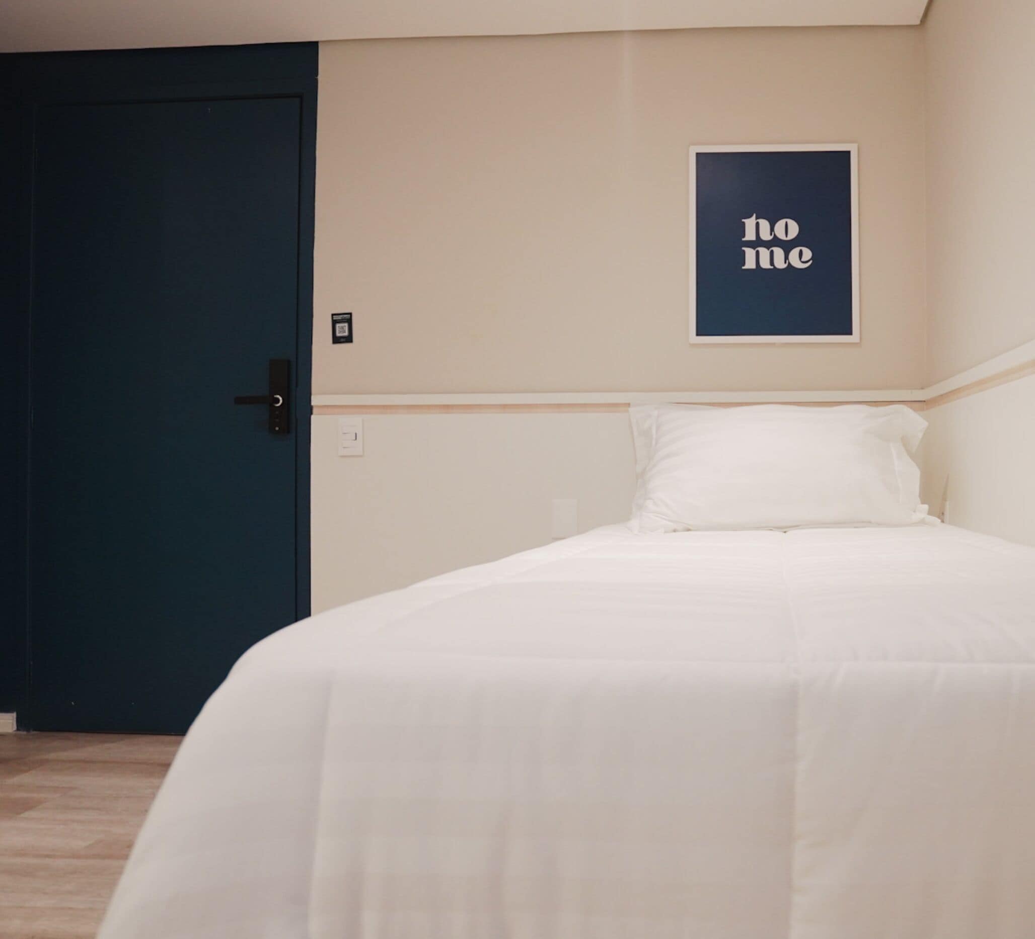 A bedroom with a bed, a door, and a wall-mounted sign.