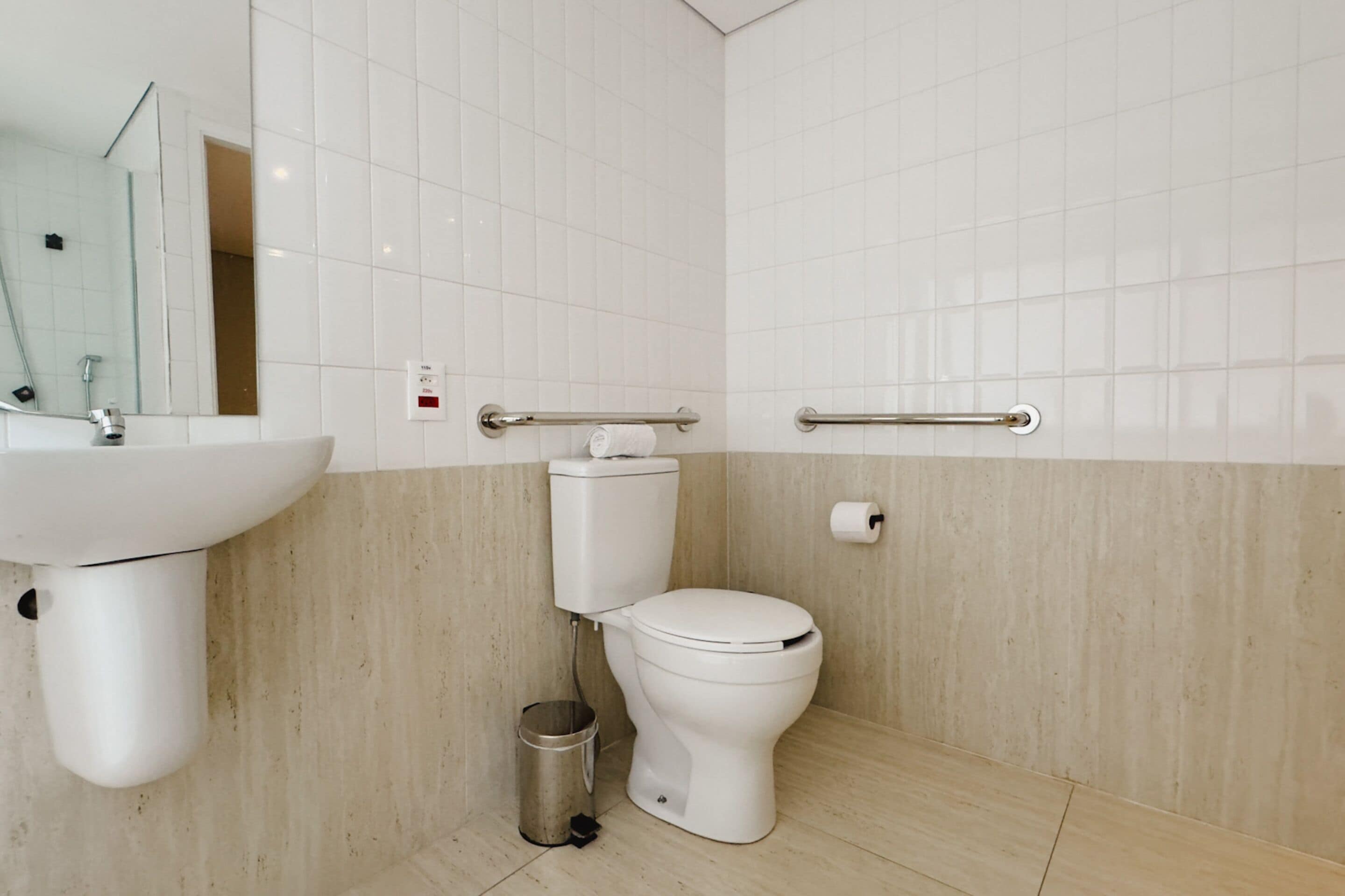 Een moderne badkamer met toilet, wastafel en handgrepen.