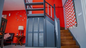 Eine Treppe mit rotem und grauem Farbdesign, einem Holzboden und einer roten Wand mit einer Uhr.
