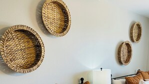 Un dormitorio ordenado con colcha a rayas, varias almohadas y adornos de pared tejidos.