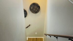 Una escalera de madera con barandilla, una ventana con planta y decoración mural.
