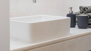 Une salle de bain avec un lavabo blanc, un distributeur de savon et une serviette.