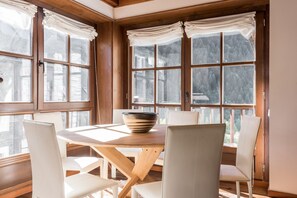 Een eethoek met een houten tafel, witte stoelen en een schaal.