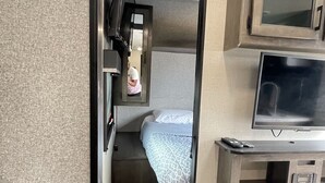 A compact RV interior with a kitchenette, a bed, and a television. -  Comfortable & Private Stay in Moreno Valley (Moreno Valley)