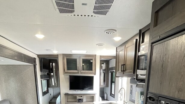 A compact RV kitchen with a central island, built-in appliances, and a seating area. -  Comfortable & Private Stay in Moreno Valley (Moreno Valley)