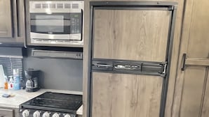 A compact kitchen with a built-in microwave, stove, and refrigerator. -  Comfortable & Private Stay in Moreno Valley (Moreno Valley)