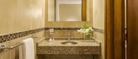 A bathroom with a granite countertop, a sink, a towel rack, and a mirror.