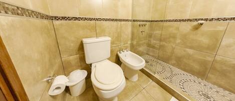 A bathroom with two toilets, a bidet, and a patterned tile border.