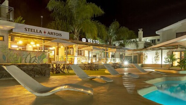 Ein Hotel mit Poolbereich, Liegestühlen und einem Restaurant namens 'Stella Artois'.