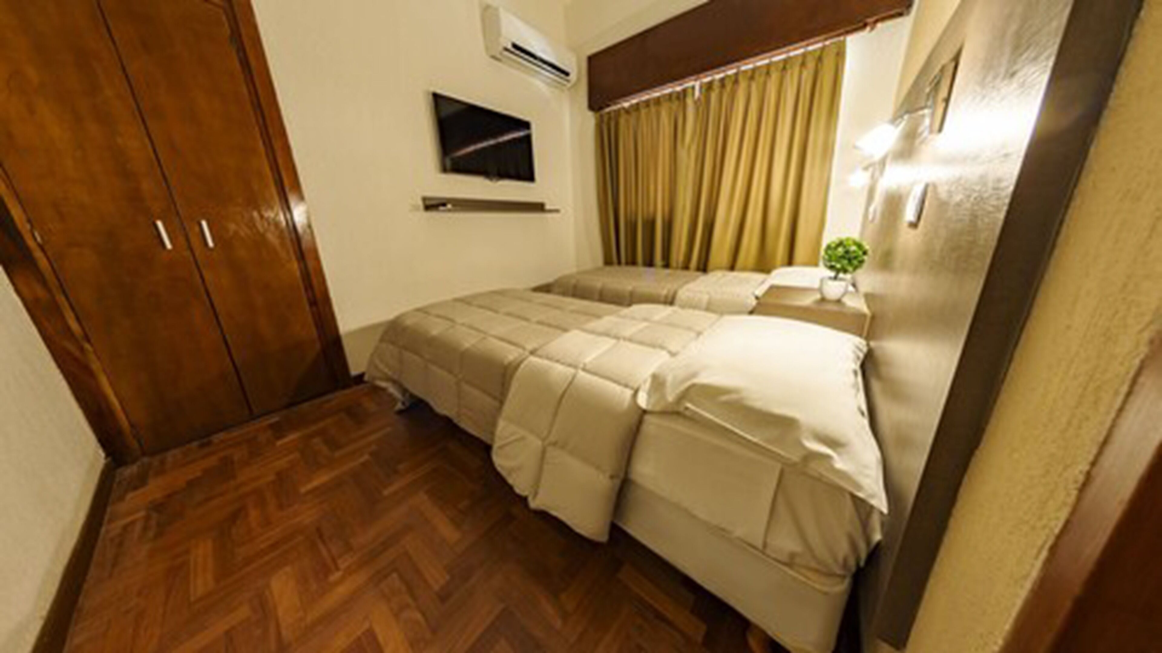 Un dormitorio con cama, armario de madera y un equipo de aire acondicionado pequeño en la pared.