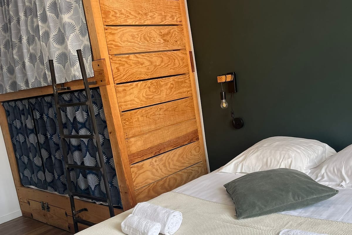 A bedroom with a bed, pillows, and a wooden wardrobe.