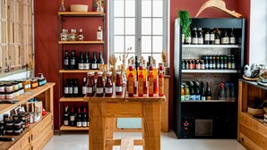 A wine cellar with wooden shelves and a central table displaying various bottles. - Auberge Koskenia (Bidart)