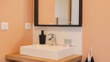 A bathroom with a white sink, black faucet, and a mirror with a black frame.