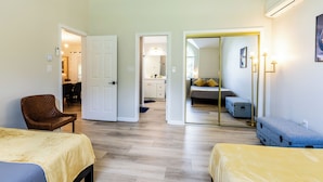Habitación de hotel con dos camas, una silla, un espejo y un baño visible a través de una puerta abierta.
