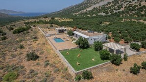 Een moderne villa met zwembad, een overdekt terras en uitzicht op het omliggende landschap.