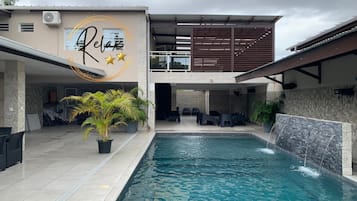 A modern building with a pool, outdoor seating, and a 'Relax' sign.