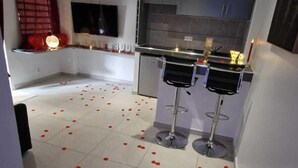 Una cocina moderna con armarios oscuros, un televisor de pantalla plana y una barra con taburetes.