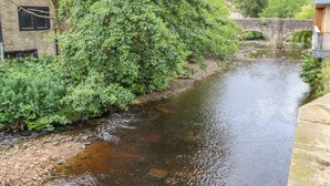 Un río que atraviesa una ciudad con edificios de piedra y un puente al fondo.